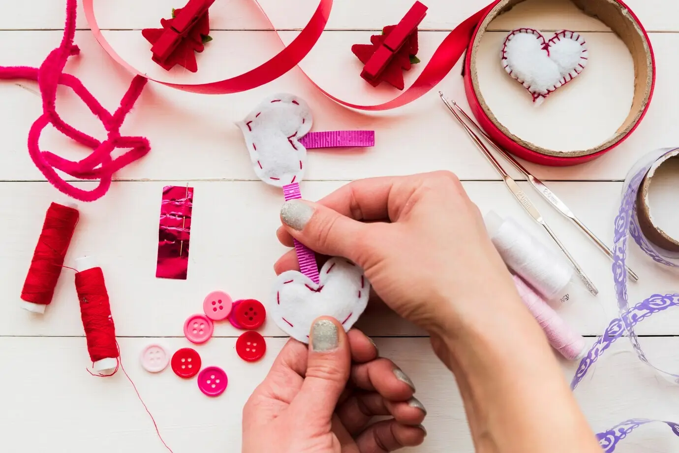 Nahaufnahme der Hand einer Frau, die die weißen Herzen auf weißem Tisch macht.